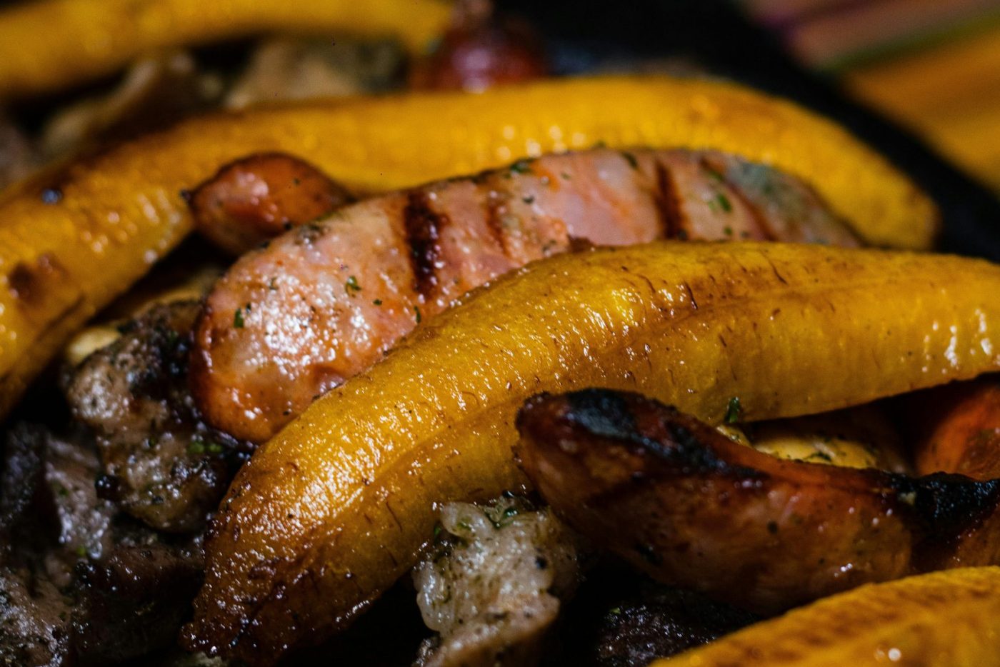Delicieux plantains grillés avec des saucisses et de la viande dans une poêle noire, parfaits pour le dîner