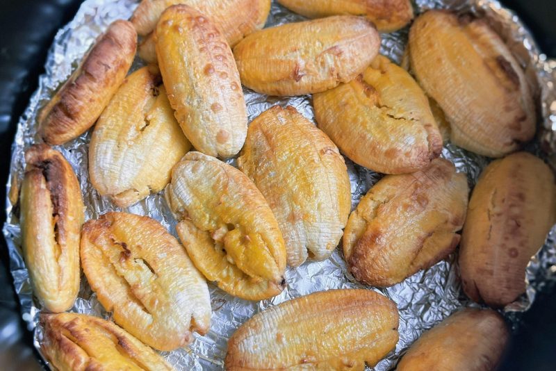 Gros plan de plantains dorés cuits au four sur du papier aluminium, idéal pour les recettes tropicales.