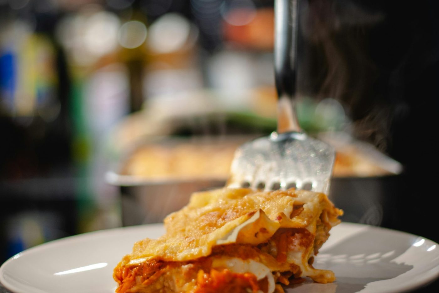 Freshly served lasagna slice on plate with steaming layers and rich sauce. Une tranche de lasagne fraîchement servie sur une assiette avec des couches fumantes et une sauce riche.