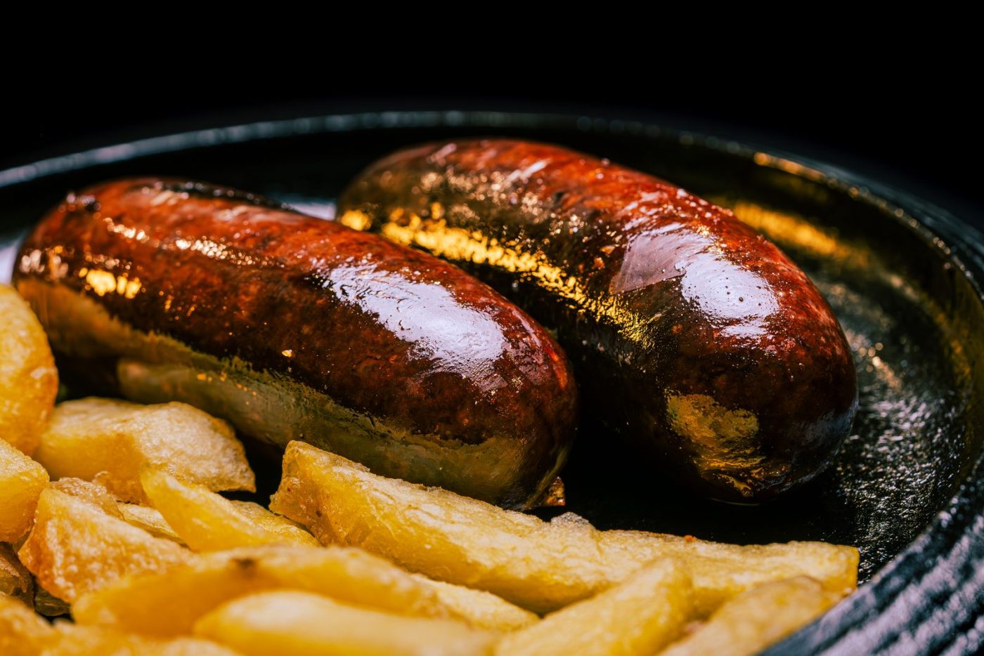 Saucisses noires grillées et frites dans un plat en fonte