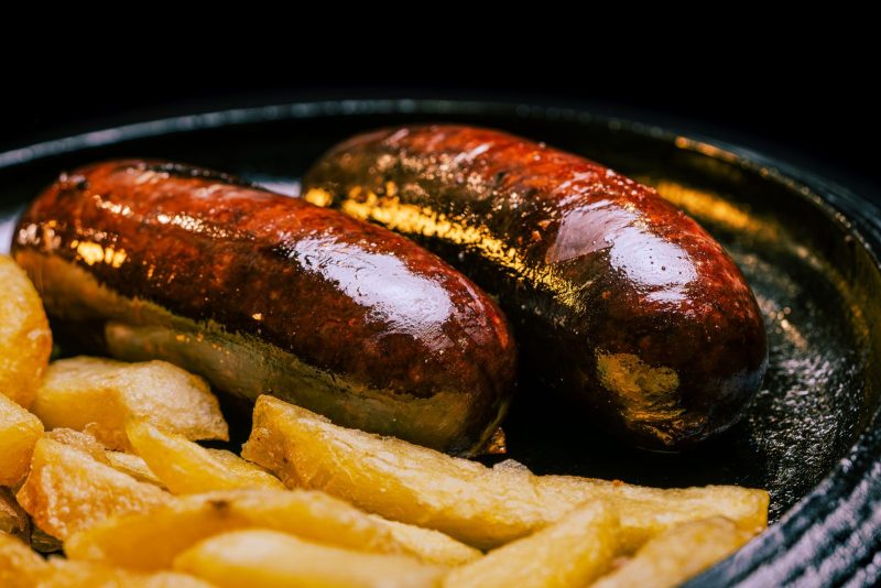 Saucisses noires grillées et frites dans un plat en fonte
