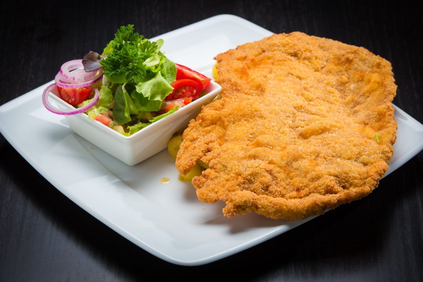 Escalope panée et salade composée sur une assiette blanche