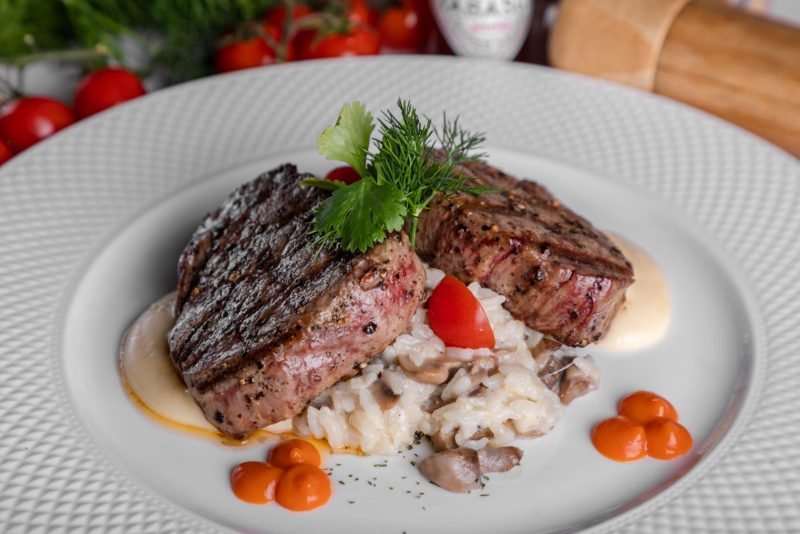 Deux tournedos grillés servis sur un risotto aux champignons